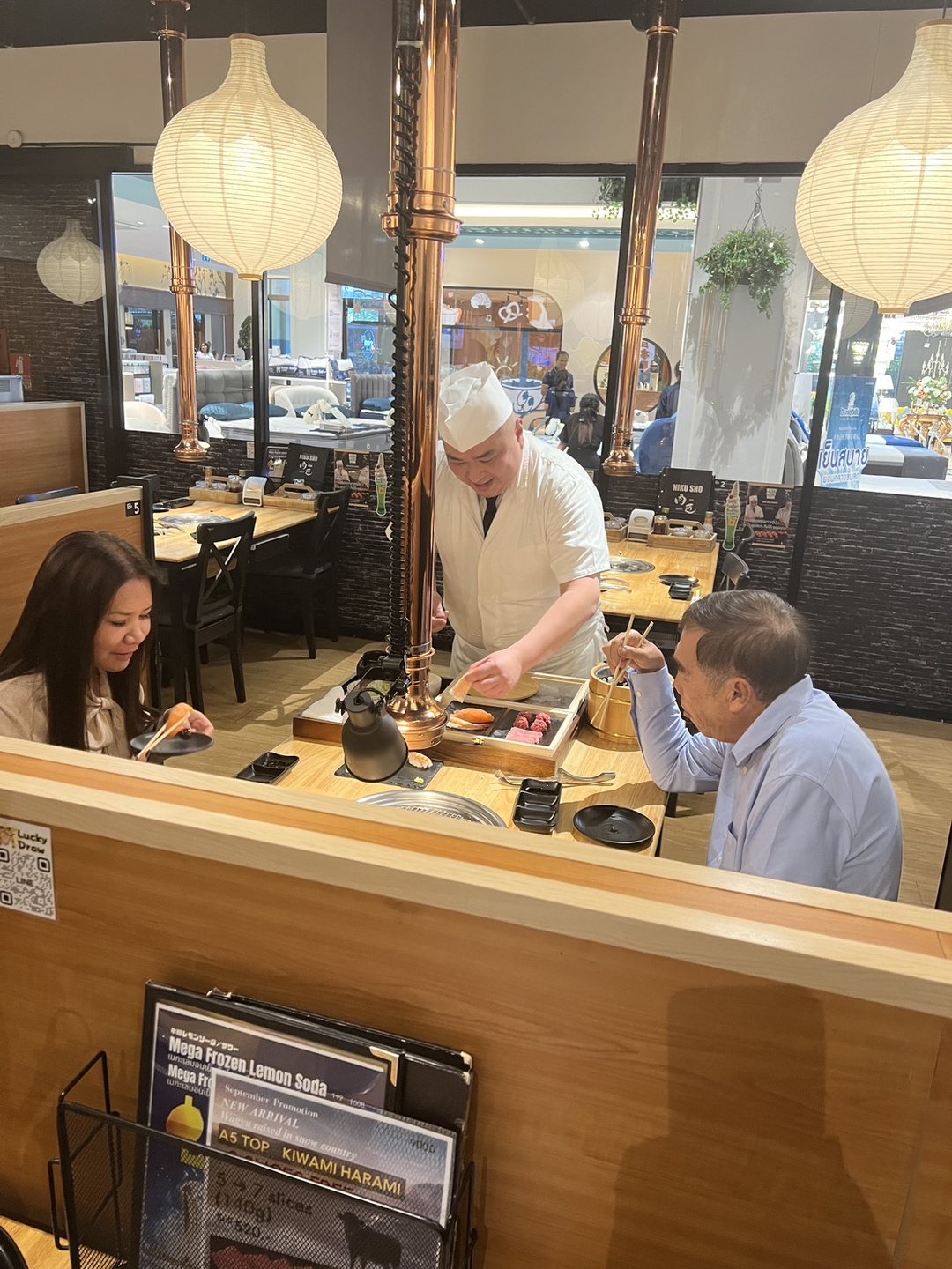 Guests at the table while the chef serves sushi